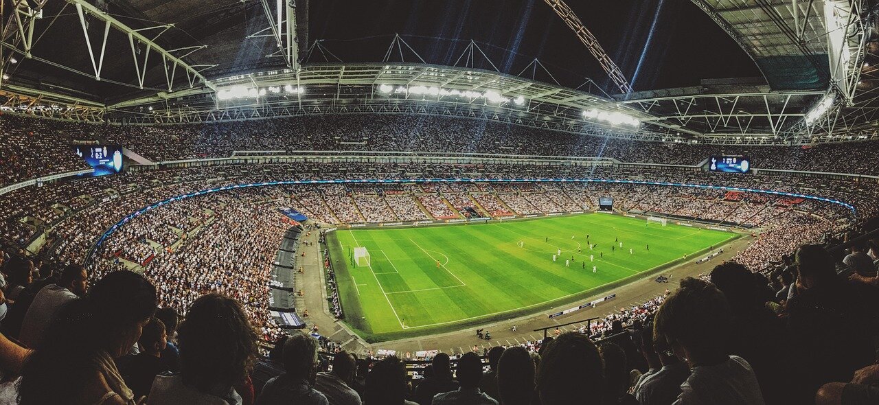 A group of friends celebrating a goal during a football match broadcast, displaying their enthusiasm and passion for the game