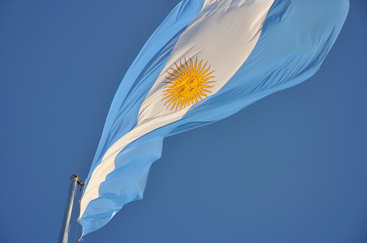Crowds of Argentine fans gather in the streets, waving banners referencing the Malvinas while singing songs to celebrate England's recent football victory.