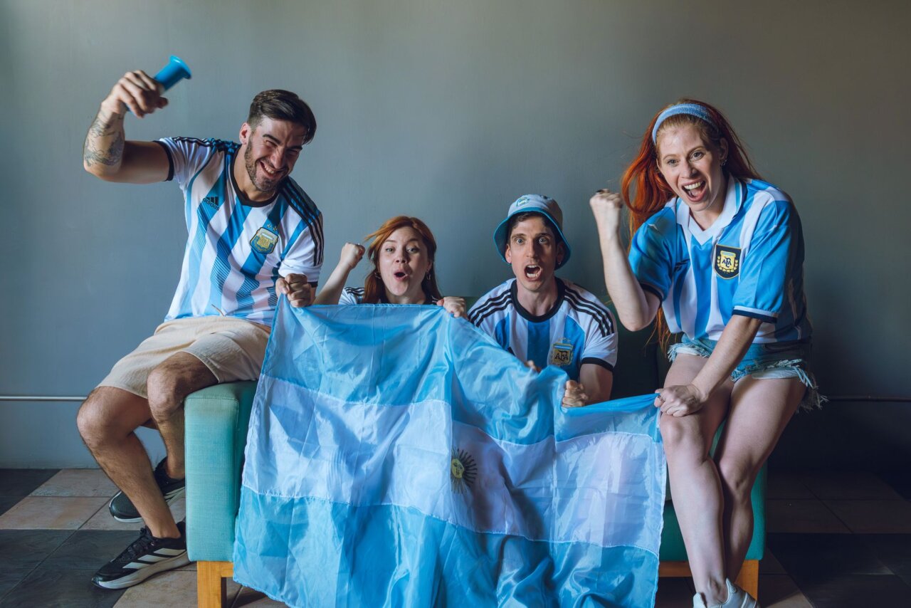 Argentine supporters erupt in joy and celebration, waving flags and chanting in unison after their team's dramatic victory