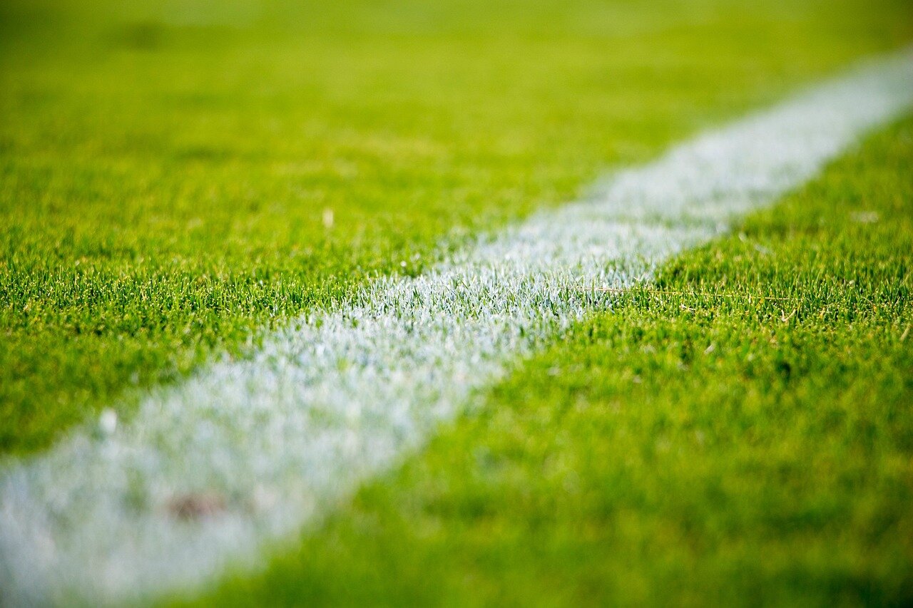Fans cheer enthusiastically in the stands as players battle for possession during a tense Premier League match.